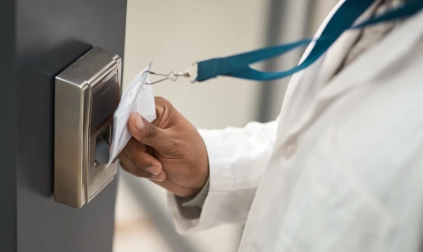 Une personne utilise une carte d'accès blanche pour déverrouiller une serrure électronique dorée sur une porte grise moderne