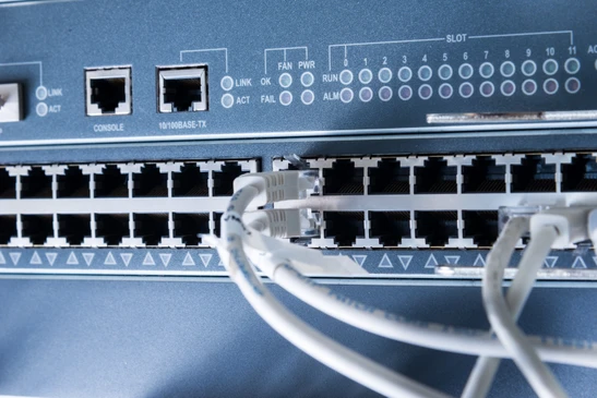 Intérieur de datacenter avec technicienne en chemise bleue utilisant une tablette tactile pour surveiller les équipements réseau