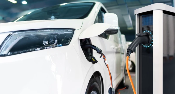 Scène extérieure urbaine avec véhicule électrique blanc en charge sur borne publique